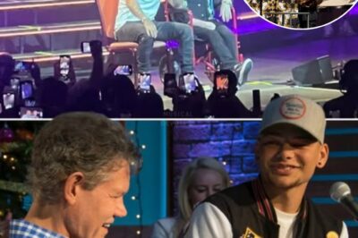Kane Brown had the entire arena holding its breath as he stepped back from the mic, revealing a living legend—Randy Travis—rolling onto the stage in his red wheelchair. For a split second, time stood still. Then, the crowd exploded in a deafening roar, the sheer emotion shaking the walls. As the first notes of Three Wooden Crosses filled the air, Kane’s smooth voice wrapped around Randy’s weathered but soul-stirring tone, creating pure magic. Tears welled in fans’ eyes as they witnessed history—two generations colliding, honoring the heart and soul of country music in a moment that would never be forgotten.
